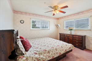 Bedroom featuring a textured ceiling, wallpapered walls, and carpet