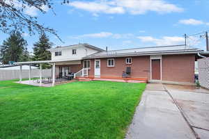Back of house featuring fence, brick siding, a patio, a yard, and metal roof