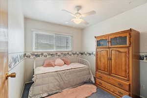 Carpeted bedroom featuring ceiling fan and wallpapered walls