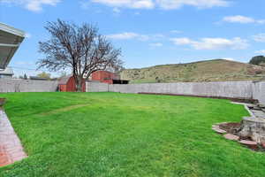 View of yard featuring a fenced backyard, a mountain view, a shed, and an outbuilding