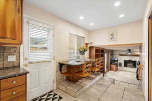 Interior space with open floor plan, recessed lighting, dark stone counters, brown cabinets, and light tile patterned floors