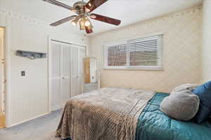 Bedroom featuring baseboards, light carpet, ceiling fan, and a closet