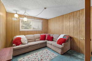 Carpeted living room with wood walls and a textured ceiling