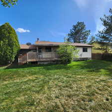 Back of property featuring a yard, a deck, and a chimney