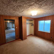 Unfurnished bedroom with wood walls, a closet, and carpet flooring