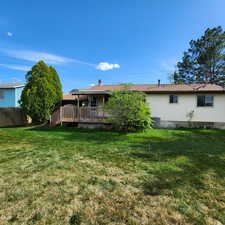 Rear view of house with a yard, fence, and a wooden deck