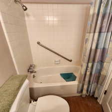 Bathroom featuring shower / bath combo with shower curtain, wood finished floors, and toilet