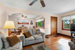 Living room with baseboards, arched walkways, ceiling fan, and wood finished floors