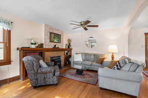 Living room featuring a ceiling fan, baseboards, wood finished floors, and arched walkways