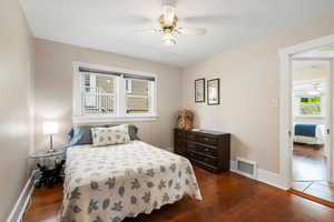 Bedroom with a ceiling fan, baseboards, visible vents, and dark wood-style floors