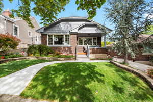 Bungalow-style house with brick siding, a front lawn, and a porch