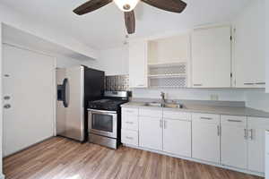 Kitchen with open shelves, a sink, light countertops, stainless steel appliances, and a ceiling fan