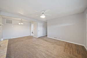 Spare room featuring baseboards, visible vents, and ceiling fan with notable chandelier