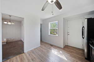 Foyer entrance with baseboards, ceiling fan, visible vents, and wood finished floors