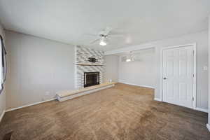 Unfurnished living room featuring carpet floors, baseboards, ceiling fan, and a fireplace
