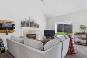 Carpeted living area with high vaulted ceiling and a fireplace