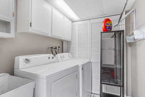 Washroom with cabinet space, tile patterned floors, a sink, and washer and clothes dryer