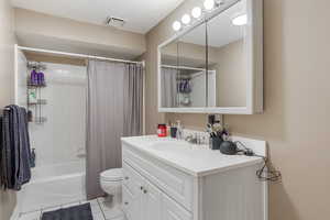 Bathroom featuring visible vents, tile patterned flooring, shower / tub combo, vanity, and toilet