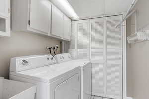 Clothes washing area featuring cabinet space, a sink, and washer and dryer