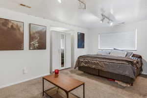 Carpeted bedroom with visible vents, baseboards, and track lighting