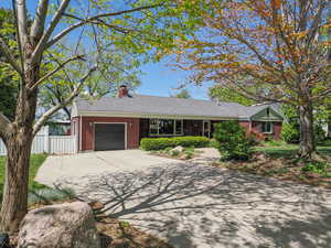 Ranch-style house with fence, brick siding, a garage, a chimney, and driveway