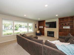Living room featuring baseboards, recessed lighting, light carpet, and a large fireplace