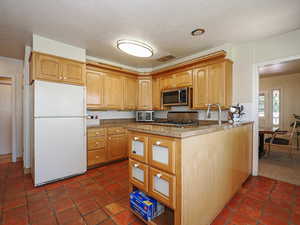 Kitchen featuring visible vents, freestanding refrigerator, stove, stainless steel microwave, and a sink