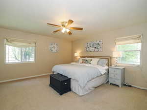 Bedroom with baseboards, multiple windows, light carpet, and ceiling fan