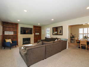 Living room with light colored carpet, recessed lighting, and a glass covered fireplace