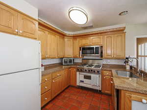Kitchen with visible vents, decorative backsplash, dark tile patterned flooring, a sink, and stainless steel appliances