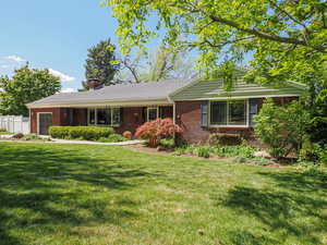 Ranch-style home with fence, a front lawn, brick siding, a garage, and a chimney