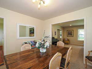 Dining space with baseboards, carpet, and an inviting chandelier