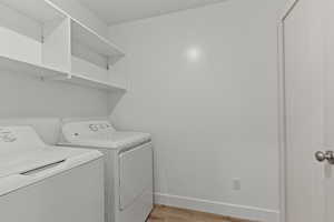 Laundry room with washing machine and clothes dryer, laundry area, baseboards, and light wood-style flooring