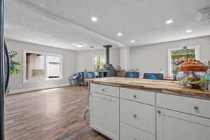 Kitchen with wooden counters, dark wood-style floors, a textured ceiling, and open floor plan