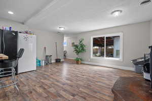 Interior space featuring baseboards, a textured ceiling, visible vents, and wood finished floors