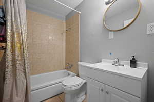 Bathroom featuring toilet, shower / bath combination with curtain, tile patterned flooring, and vanity