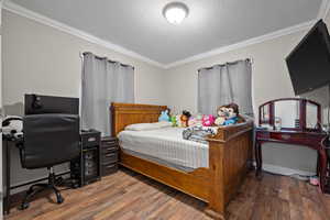 Bedroom featuring crown molding, a textured ceiling, and wood finished floors