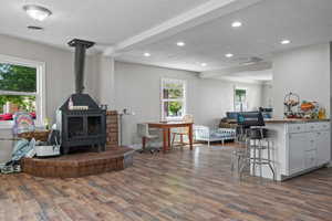 Living area with dark wood-style flooring, a wood stove, a textured ceiling, recessed lighting, and visible vents