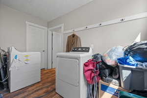 Laundry area with separate washer and dryer, laundry area, wood finished floors, and a textured ceiling