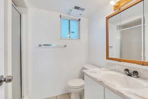 Full bathroom featuring tile patterned flooring, a shower with shower door, toilet, and visible vents
