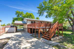 Rear view of house with fence, a wooden deck, a shed, stairs, and driveway