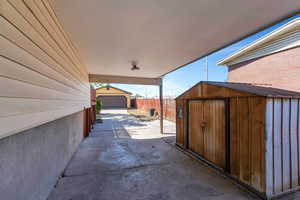 View of patio with driveway, fence, and an outdoor structure