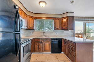 Kitchen featuring a sink, a peninsula, black appliances, and a wealth of natural light