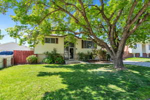 Bi-level home with brick siding, a front lawn, and fence