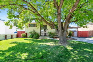 View of front of property featuring brick siding, fence, and a front lawn