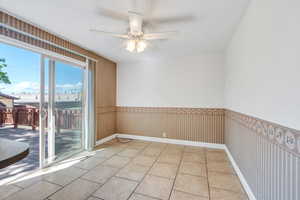 Empty room with light tile patterned floors and a ceiling fan