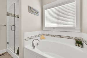 Bathroom with a garden tub, a healthy amount of sunlight, and a shower stall