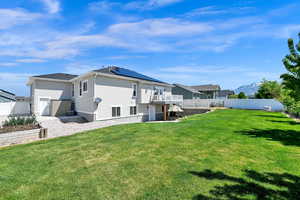 Rear view of property with a yard, a deck, a fenced backyard, and stucco siding
