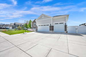 View of side of home featuring board and batten siding, driveway, a gate, fence, and a yard