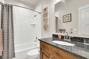 Bathroom with vanity, shower / tub combo, and toilet
